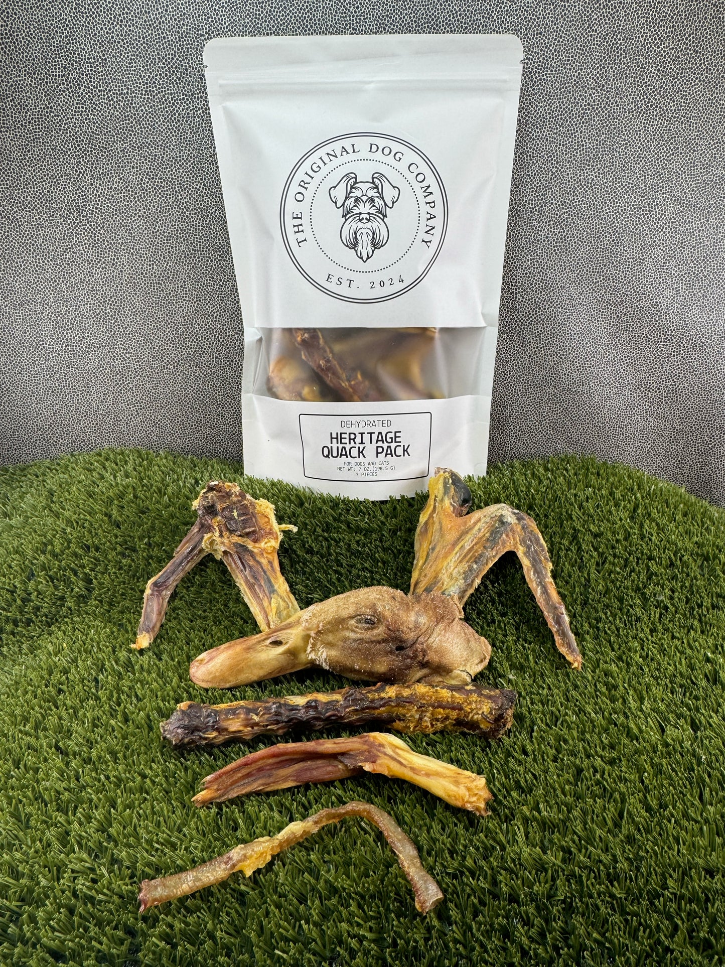 Dog treats on a green surface with an open package of treats from 'The Original Dog Company' visible.