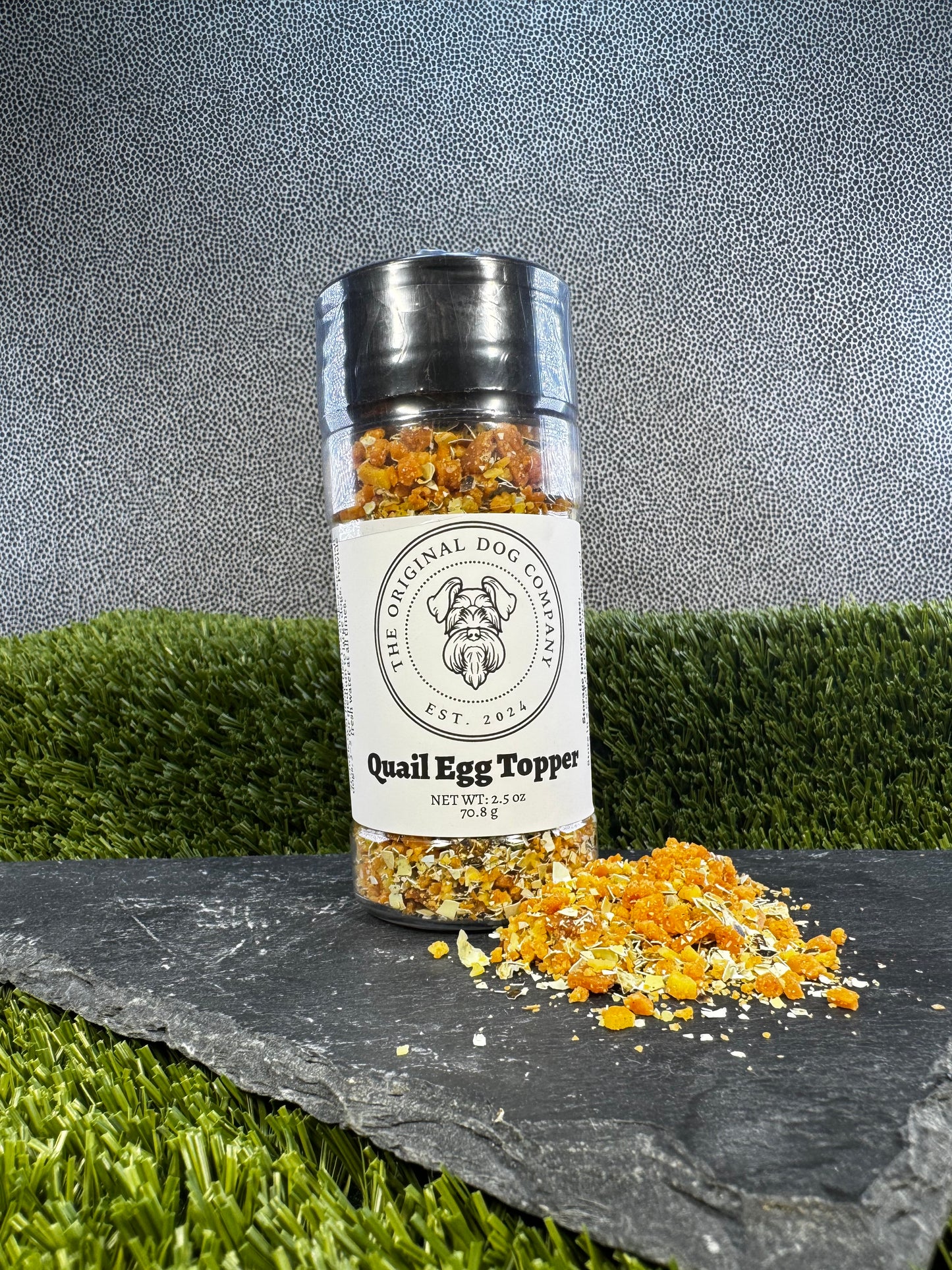 Bottle of Quail Egg Topper from The Original Dog Company on a grassy background